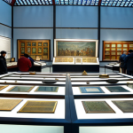 **

"A panoramic view inside the National Museum of Mongolian History in Ulaanbaatar, showcasing artifacts from the Mongol Empire era, including weapons, traditional clothing, and religious items. The scene is well-lit, emphasizing the intricate details of the exhibits. Visitors are observing the displays with interest. Display cases and informational signs are visible. Fully clothed visitors, appropriate content, safe for work, perfect anatomy, correct proportions, professional museum photography, high quality, modest."

**